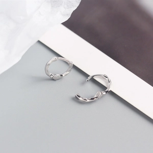 Macro detail of silver twisted Mobius hoop earrings showing open and closed mechanism