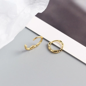 Close-up of golden S925 sterling silver ear cuffs featuring a minimalist twisted texture