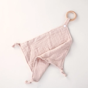 Detail of pink cotton muslin baby security blanket with a natural wooden teething ring