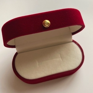 Macro view of wine red velvet jewelry box with cream lining and metal clasp closure