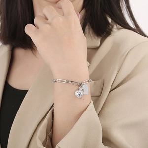 Detailed shot of stainless steel chain bracelet featuring two heart charms on wrist