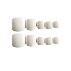 Detail view of two rows of glossy white press-on toenails in graduated sizes