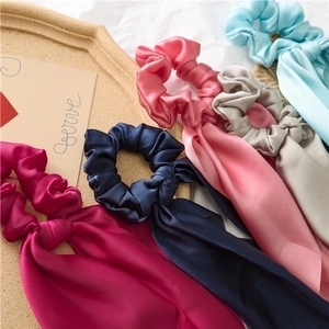 Detail of five assorted satin scrunchies with long ribbons on a beige tray