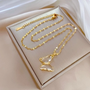 Detailed macro of gold butterfly pendant with crystals on a beige jewelry cushion