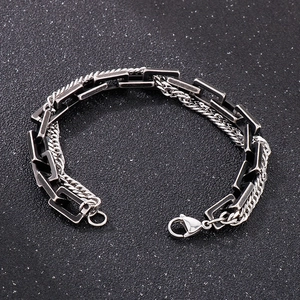 Detail of a double-layered metal bracelet with black square links and silver woven chain