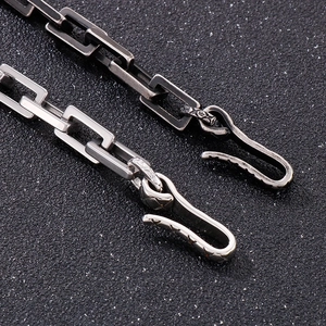 Macro shot of silver and gun-black geometric chain links with S-hook buckle detail