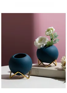 Detail of matte ceramic globe vases in dark teal with geometric gold metal stands