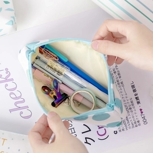 Hand opening a light blue canvas pencil case filled with stationery on a bright desk