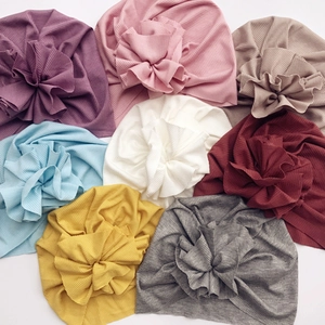 Detailed view of bohemian rib-knit baby hats in multiple colors with large handmade flowers