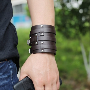 Close-up of a wide dark brown braided leather cuff bracelet with metal rivets and buckle