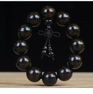 Macro shot of dark black pearl wood beads featuring golden star textures and knot