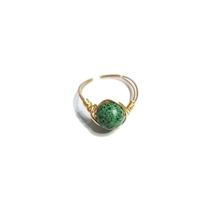 Close-up of handmade gold wire wrapped ring with a green spotted natural stone