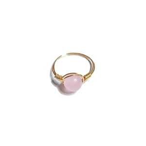 Detail of handmade gold wire-wrapped ring featuring a smooth round pink bead gemstone