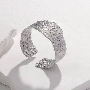 Detailed macro view of silver hammer texture on wide stainless steel cuff bracelet