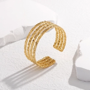 Detailed view of golden irregular hammered texture on a multi-layer open steel bangle