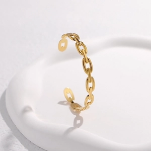 Dettaglio del bracciale a catena dorata minimalista su un vassoio decorativo