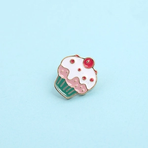 Detail of pink cake enamel pin with white icing and a red cherry on top