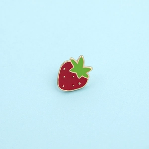 Detail of red strawberry enamel brooch with golden plating and green leaf accents