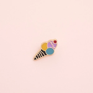 Detail of a colorful enamel ice cream cone brooch with red cherry on pink background
