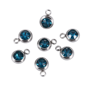 Detailed view of round stainless steel charms with multifaceted sea blue crystals