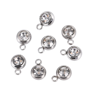 Close-up of circular stainless steel birthstone pendants with clear crystal stones