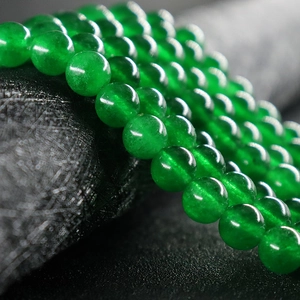Cuentas redondas de calcedonia natural verde pulida para joyería DIY en fondo con textura