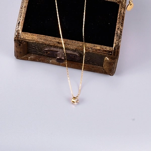 Gold plated stainless steel necklace with round cubic zirconia pendant on jewelry box