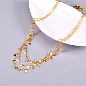 Detailed close-up of a layered gold geometric necklace with discs on a ceramic plate