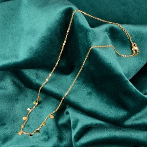 Detailed close-up of golden necklace with round pendant charms on green velvet