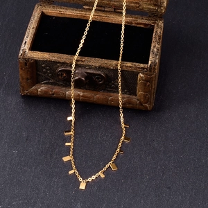 Golden necklace with geometric rectangle pendants displayed in a vintage wooden jewelry box
