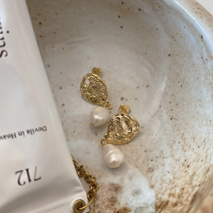 Detailed shot of hammered silver and baroque pearl earrings in a ceramic bowl