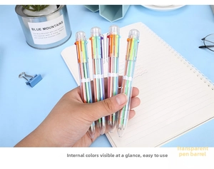 Mano che tiene una penna a sfera trasparente a 6 colori su una scrivania con cancelleria