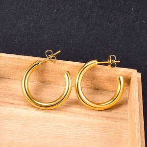 Detailed top view of gold thick hoop earrings with polished finish on a wooden display stand