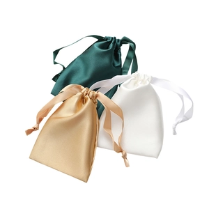 Three satin drawstring storage pouches in dark green, gold, and white silky fabric