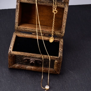Detail of 18K gold plated bamboo chain necklace with zircon pendant and logo tag