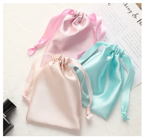Detail view of pink, gold and blue satin drawstring bags with silky ribbon closure