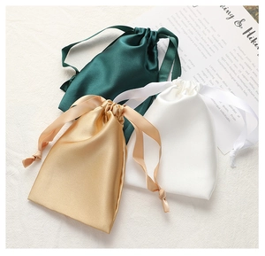 Detailed view of gold, green and white silk satin drawstring pouches for jewelry storage