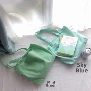 Détail des sacs fourre-tout en toile minimalistes en vert menthe et bleu aqua sur un tissu