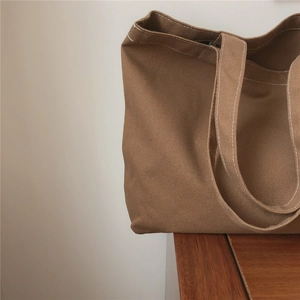 Détail du sac cabas en toile marron avec des coutures blanches contrastées