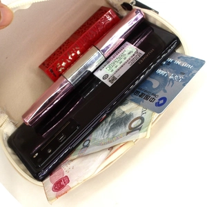 Detailed internal view of beige shell clutch showing spacious capacity for phone and makeup