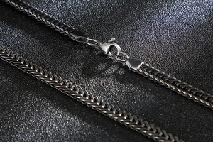 Macro detail of men's stainless steel woven chain with a secure lobster clasp
