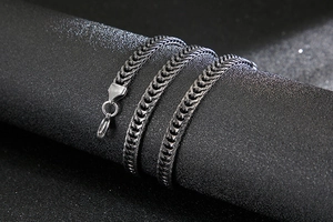Detail of vintage silver wheat chain link with lobster clasp on a dark surface