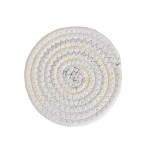 Macro view of a round white cotton woven coaster with colorful zigzag stitching detail