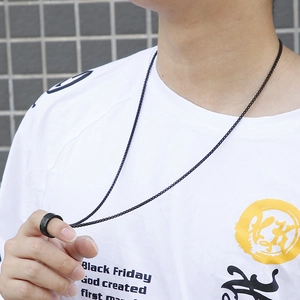 Men's black spinning mantra necklace in titanium steel worn by model on grey background