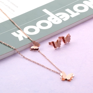 Gros plan détaillé de la parure collier et boucles d'oreilles papillon en or rose mat