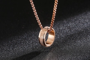 Macro shot of rotatable rose gold ring pendant with engraved Sanskrit mantra symbols