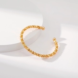 Brazalete abierto dorado minimalista con textura de grano fino y cuentas redondas