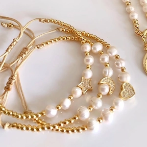 Detailed view of beaded bracelets featuring star moon and heart charms with pull cords