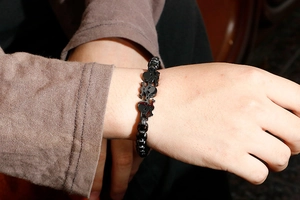 Detail of matte black skull charm links on a punk style stainless steel biker bracelet