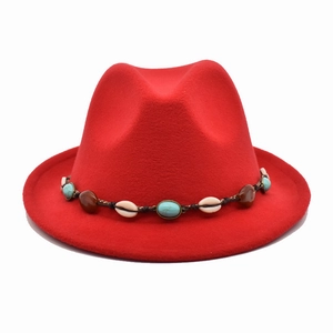 Détail d'un chapeau en feutre rouge avec ruban décoratif bohème en coquillages et perles